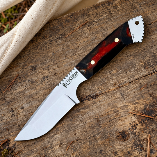 Cochran Tanto Skinner with Midnight Sun handle on a camp table in an illustrative outdoor setting.